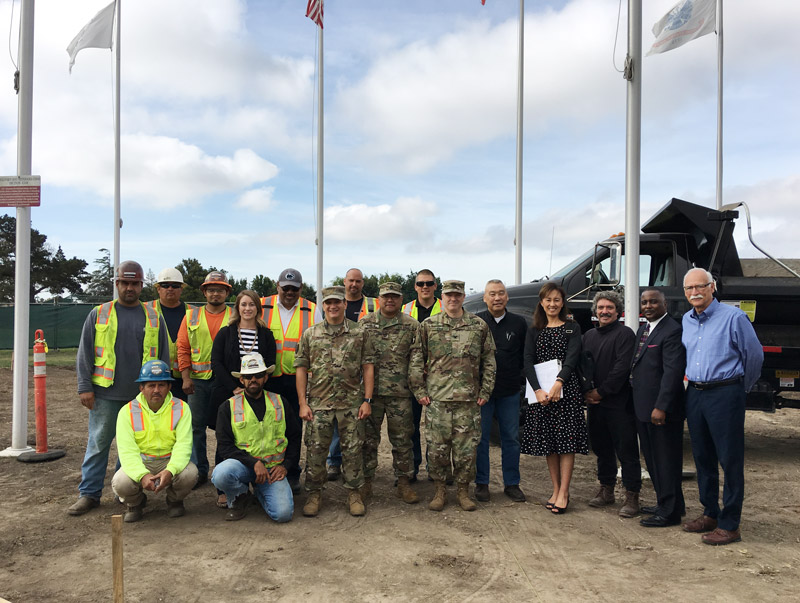 group of members from District 2, construction workers, and veterans at the construction site of the memorial